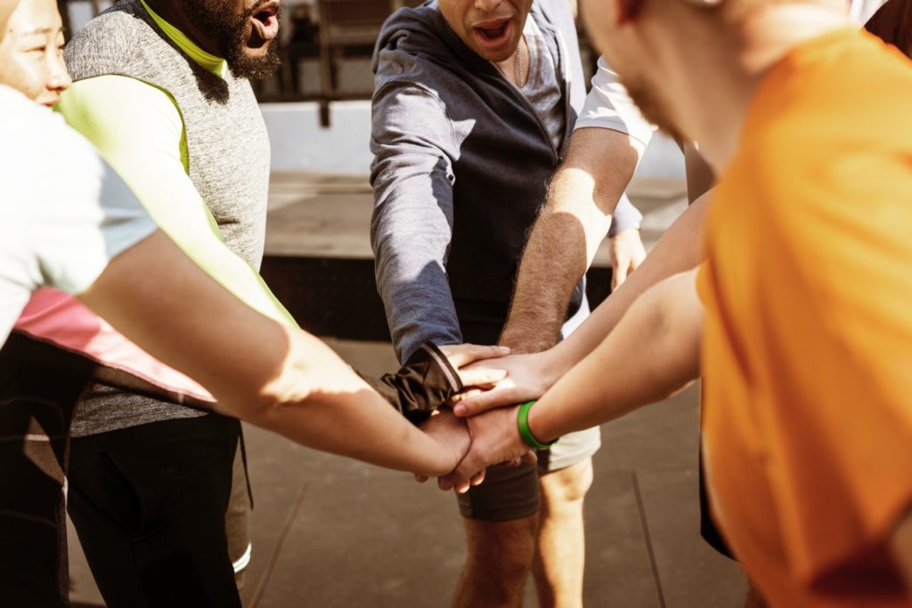 Group of people with their hands brought to the center of a huddle
